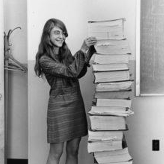 Photo de Margaret Hamilton posant à côté des livres contenant les programmes qu'elle a codé pour les modules Apollo